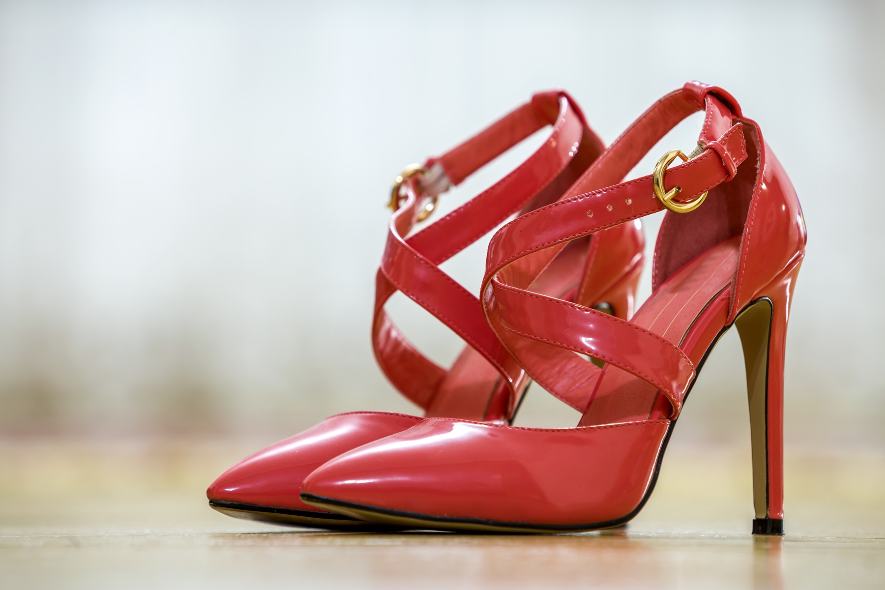 Pair of fashionable high heel leather red cut-out female shoes with golden buckles. Style and fashion, modern footwear concept.